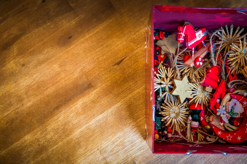 Bright and colorful handmade Christmas ornaments in a box on a wooden desk, perfect for holiday decor.