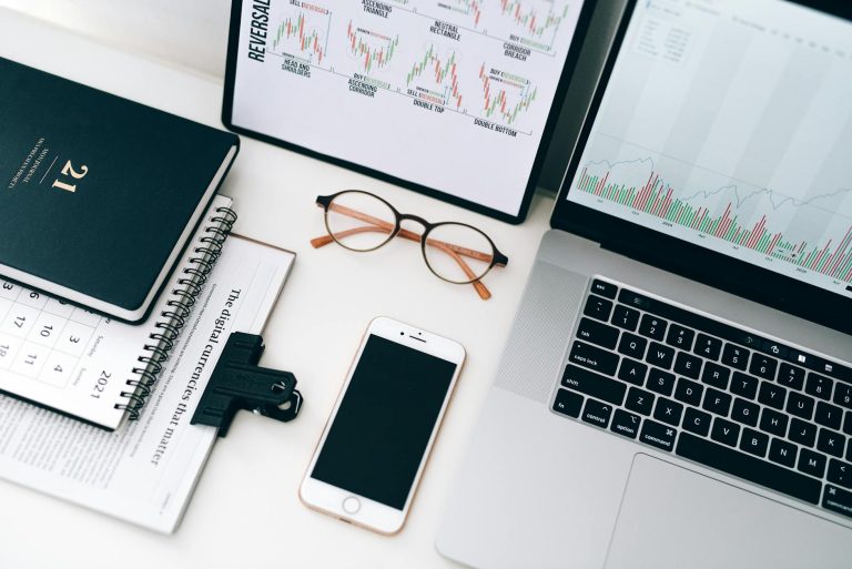 Organized workspace featuring laptop, smartphone, and graphs displaying financial data.