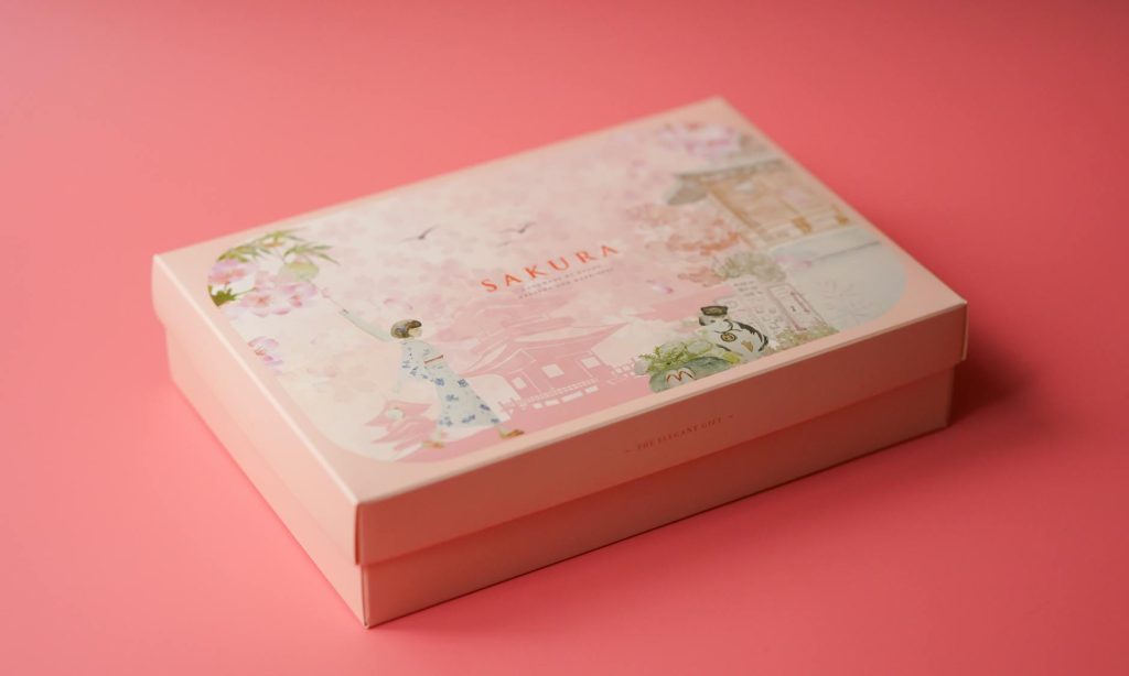 A beautifully designed Sakura gift box with floral illustrations on a soft pink background.
