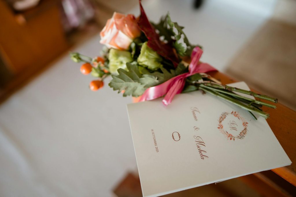 Close-up of a wedding program with a floral bouquet beside it, capturing elegant wedding decor.