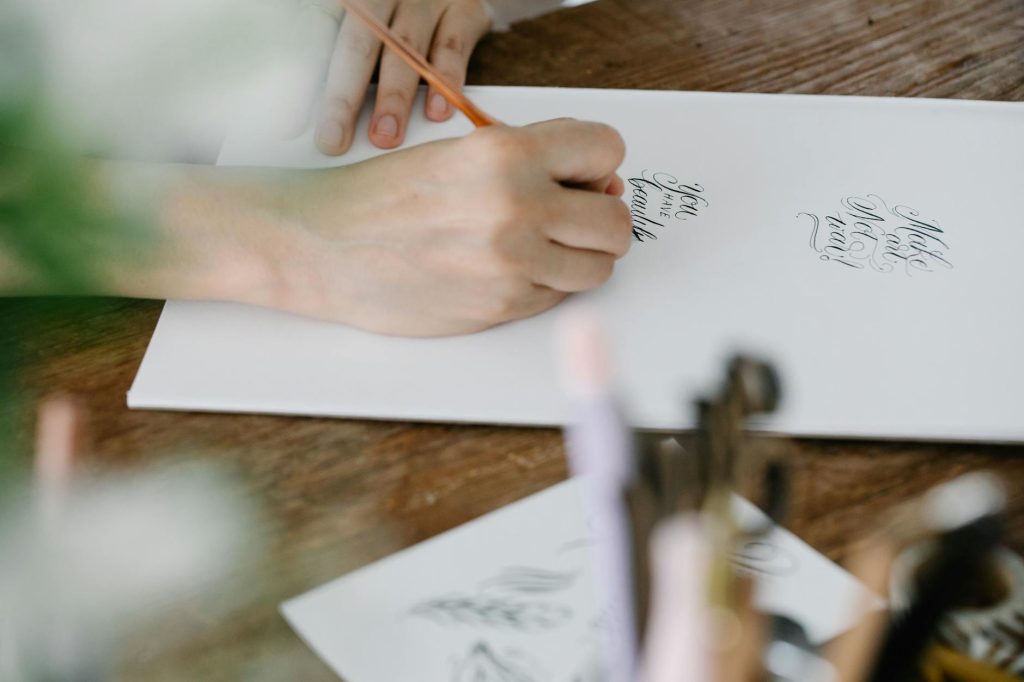 Close-up of elegant calligraphy being written, showcasing artistic hand lettering on a white sheet.