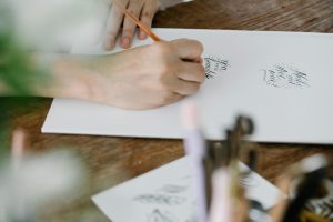 Close-up of elegant calligraphy being written, showcasing artistic hand lettering on a white sheet.