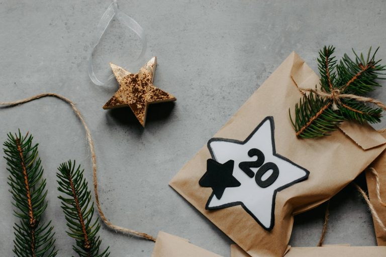 Aesthetic holiday gift packaging with stars on a gray background, featuring evergreen branches.