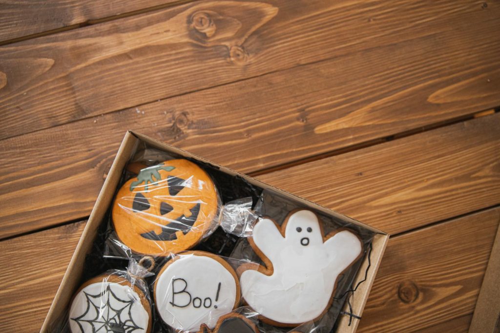 Fun Halloween-themed cookies in a box placed on a rustic wooden surface.
