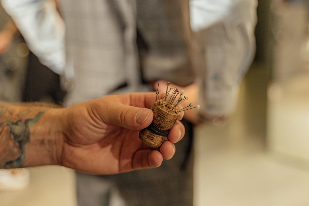 Close-up of a hand holding a handmade cork pin cushion in an artistic environment.