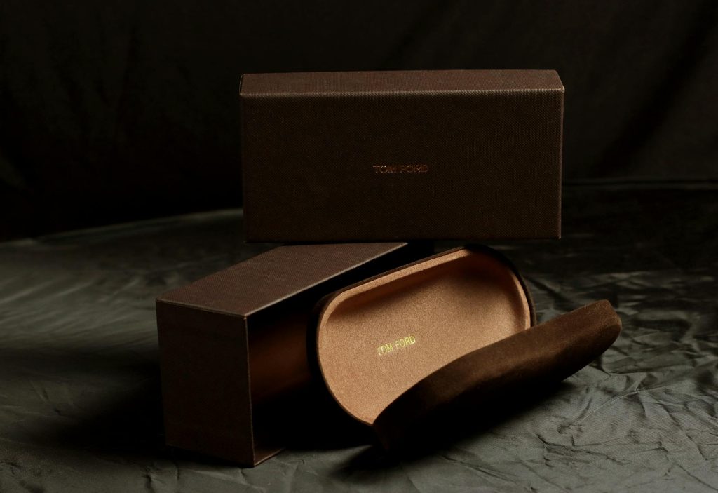 Tom Ford eyeglasses case and box on a black backdrop, showcasing luxury and sophistication.