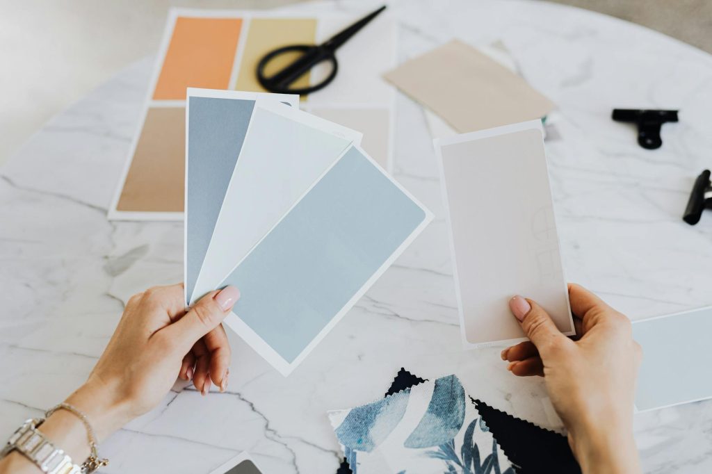Hands holding color swatches and fabric samples for creative design projects.