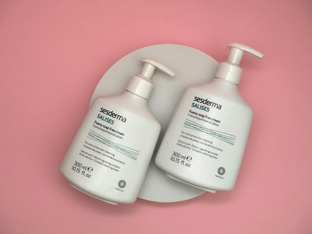 Sesderma Salises Foamy Soap Free Cream bottles on a pink background provide a skincare aesthetic.