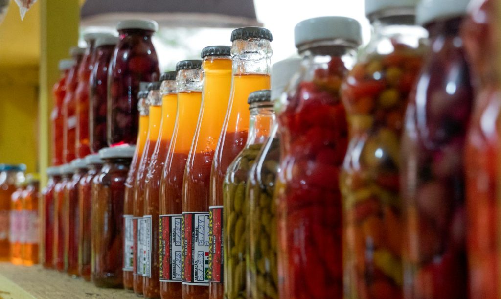 Vibrant assortment of pickled and preserved vegetables in glass jars on display in Morretes, Brazil.