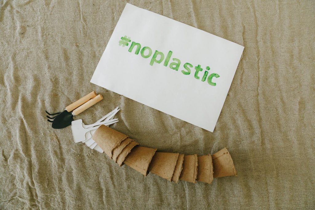 Top view of sustainable gardening tools on fabric with '#noplastic' sign.