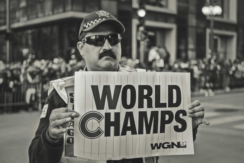 A man holds a 'World Champs' sign during a celebratory parade. Monochrome image.