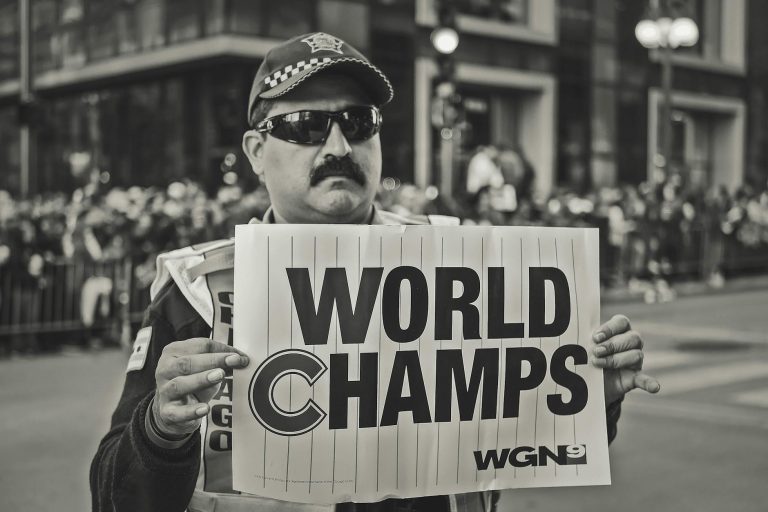 A man holds a 'World Champs' sign during a celebratory parade. Monochrome image.