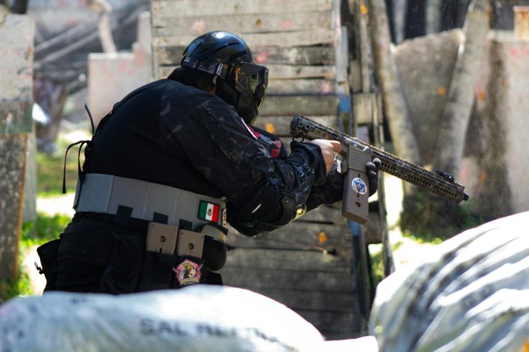 A player in full gear engages energetically in an outdoor paintball match.