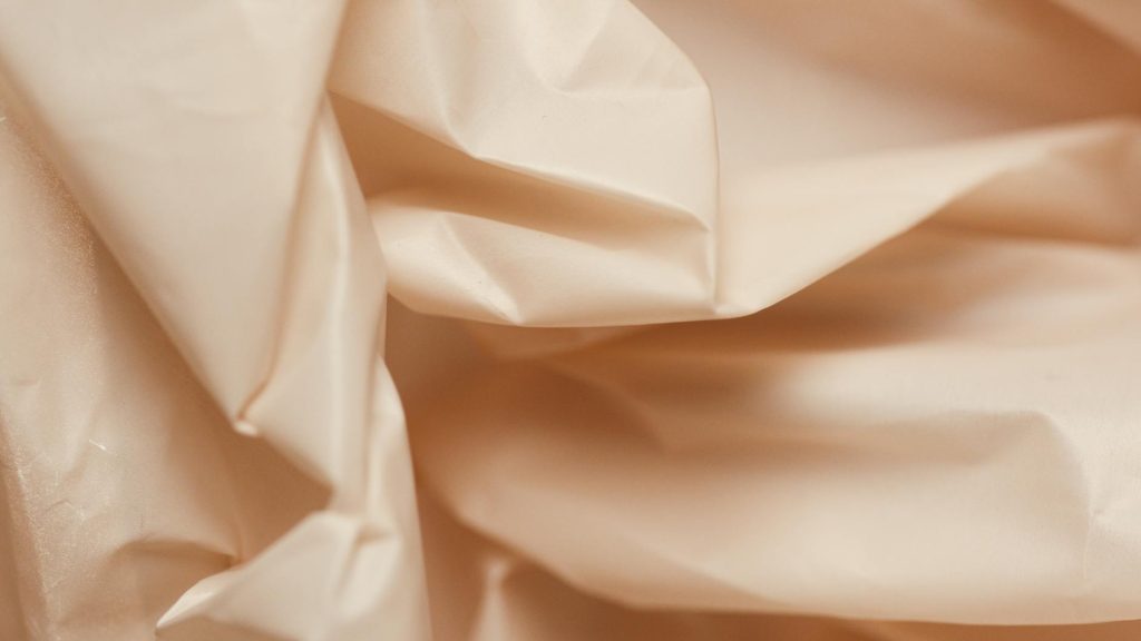 Close-up of crumpled beige paper, offering a textured and elegant background.