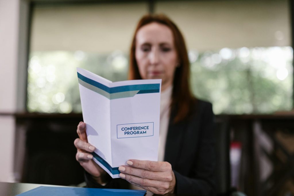 Businesswoman examining the conference program in a meeting room setting.