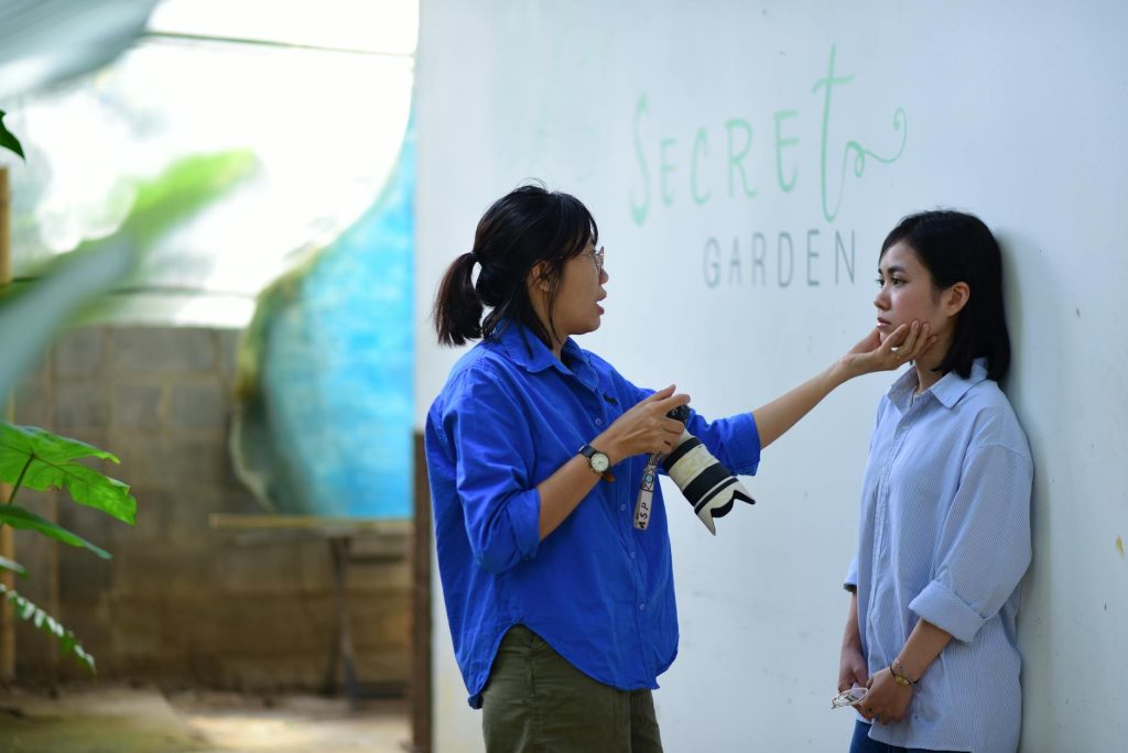 A photographer guides a model during a photoshoot at the Secret Garden, showcasing artistic direction and modeling.