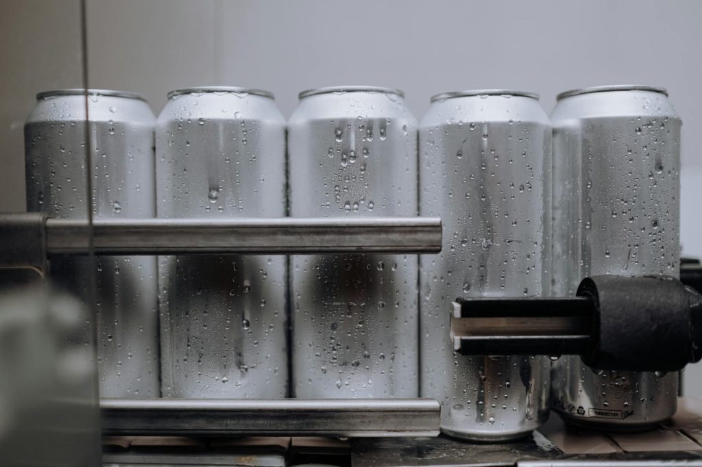 Close-up of condensation-covered aluminum cans on a production line, highlighting cool refreshment.