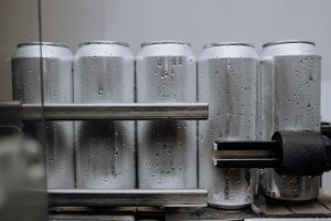 Close-up of condensation-covered aluminum cans on a production line, highlighting cool refreshment.