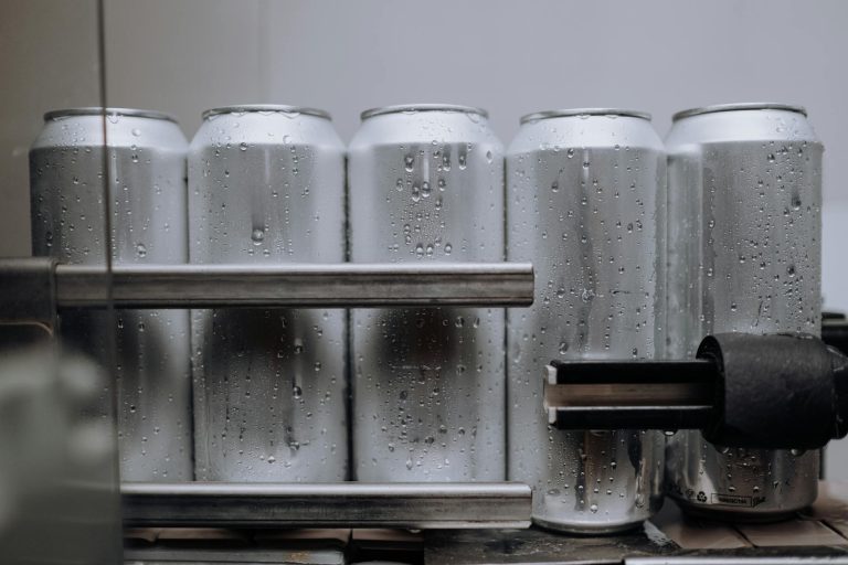 Close-up of condensation-covered aluminum cans on a production line, highlighting cool refreshment.