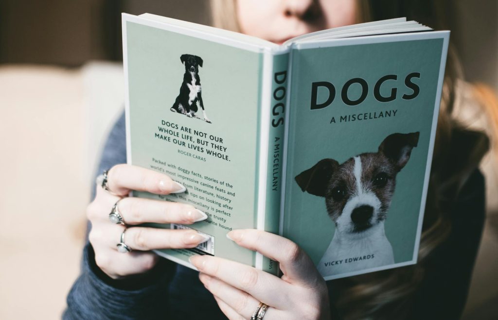Close-up of a person holding and reading a book about dogs, indoors.