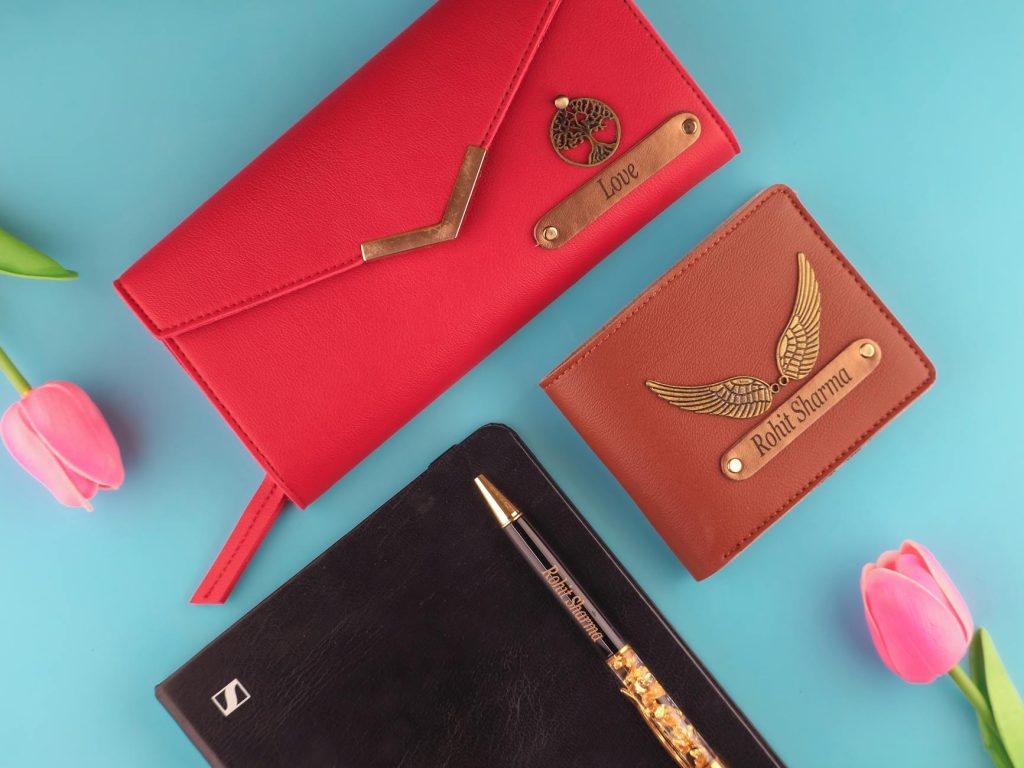 Elegant leather wallets, a notebook, and pink tulips in a stylish flat lay.