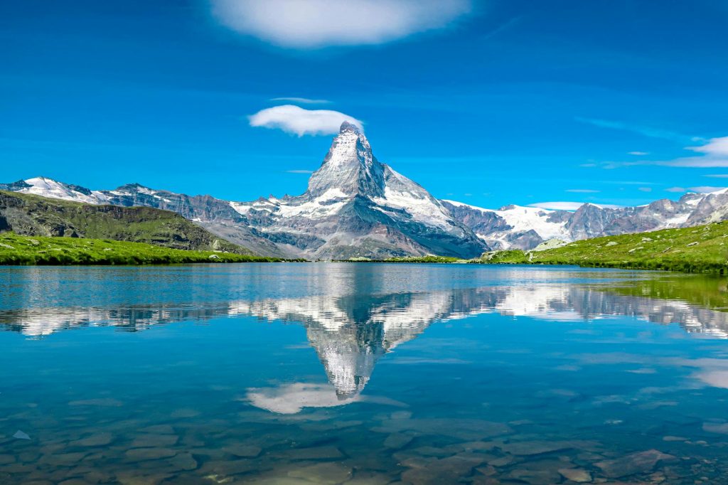 Breathtaking view of the Matterhorn reflecting in a serene Swiss lake under a clear blue sky.