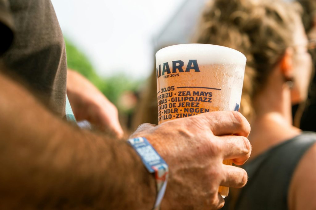 Close-up of a person holding a beer cup at an outdoor music festival.