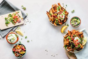 Colorful flat lay featuring sweet potato fries, guacamole, and fresh veggies, perfect for a healthy meal.