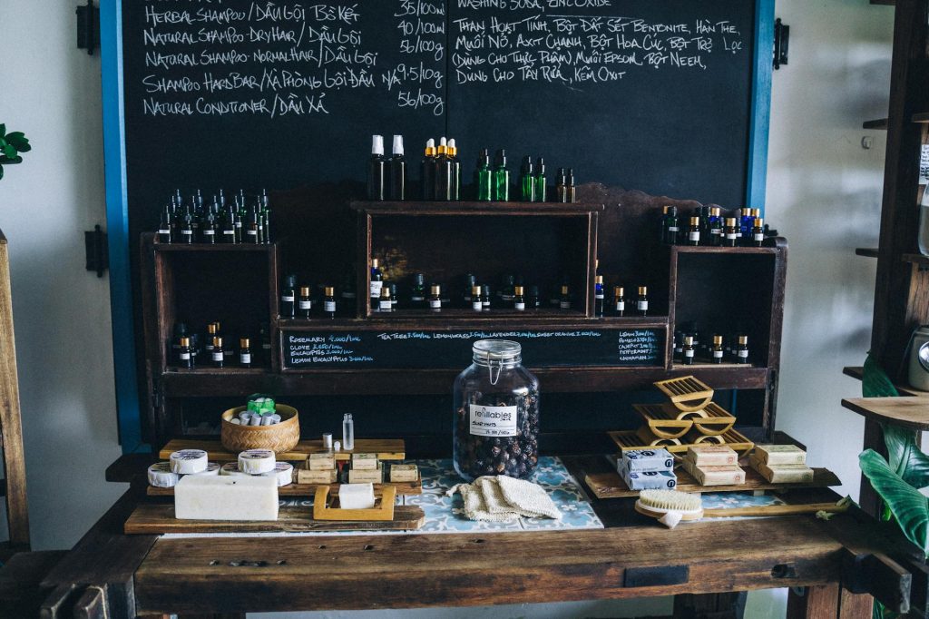 Natural cosmetic products displayed on rustic shelves in an apothecary setting.