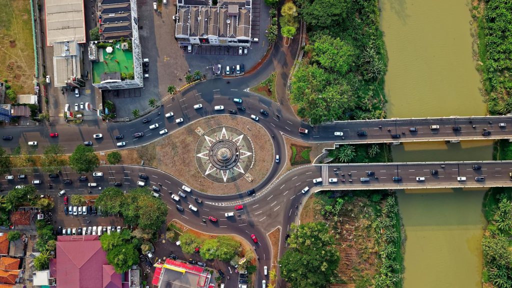 Drone view of a roundabout and bridge in Kelapa Dua, showcasing urban traffic and landscape.