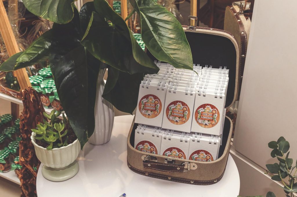 Elegant indoor arrangement of plants with notepads in a vintage suitcase on a table.