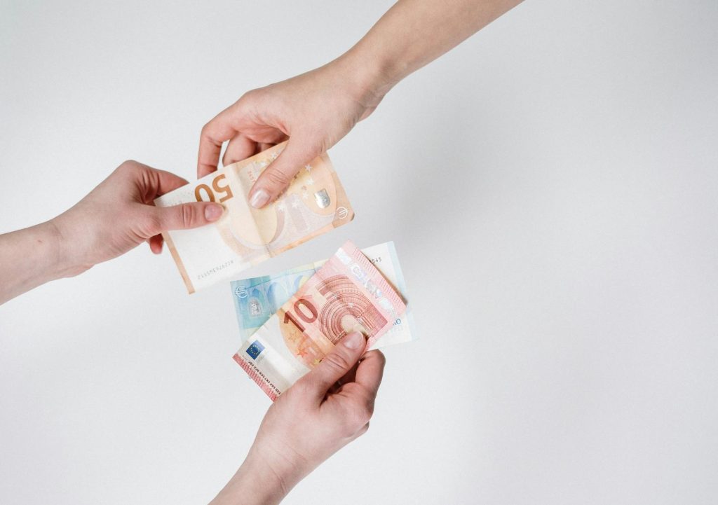 Close-up of hands exchanging euro bills, symbolizing finance and transaction.