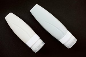 Two white skincare tubes placed on a black background, showcasing minimalist design.