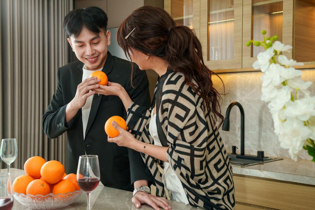 A couple sharing fresh oranges in a stylish kitchen, creating a warm and inviting atmosphere.