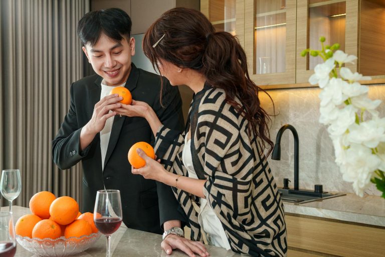 A couple sharing fresh oranges in a stylish kitchen, creating a warm and inviting atmosphere.