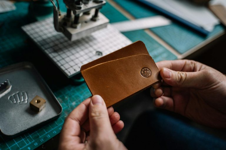 Close-up of a handmade leather card holder with an embossed logo.