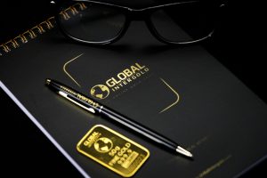 An elegant setup with a notebook, pen, and gold bar, embodying luxury and style.