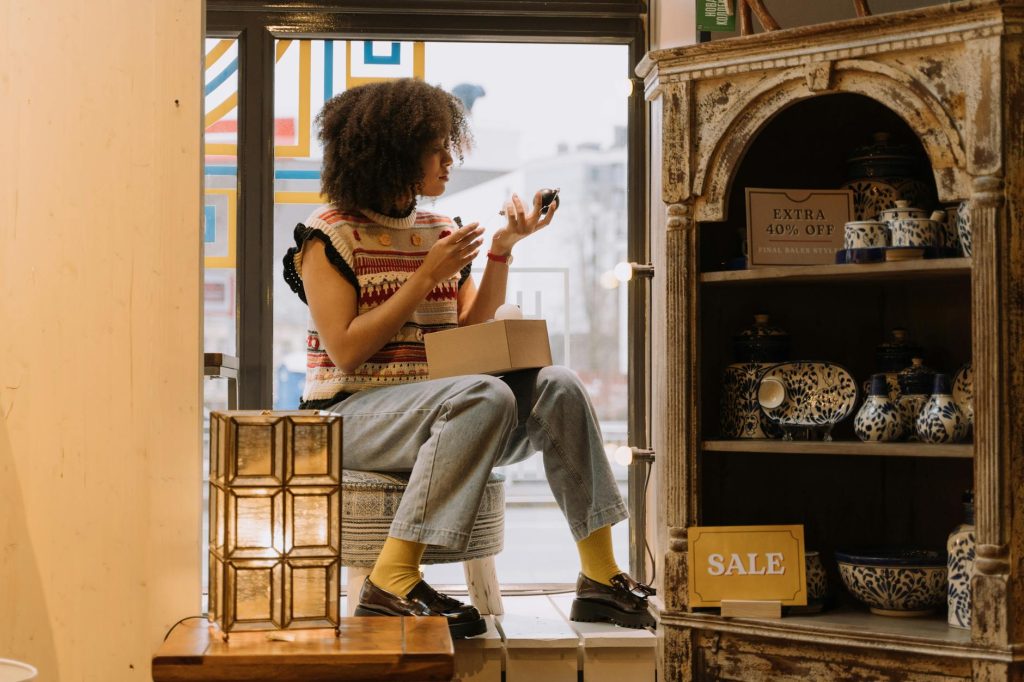A young woman promoting a sale in a cozy antique shop filled with ceramics.