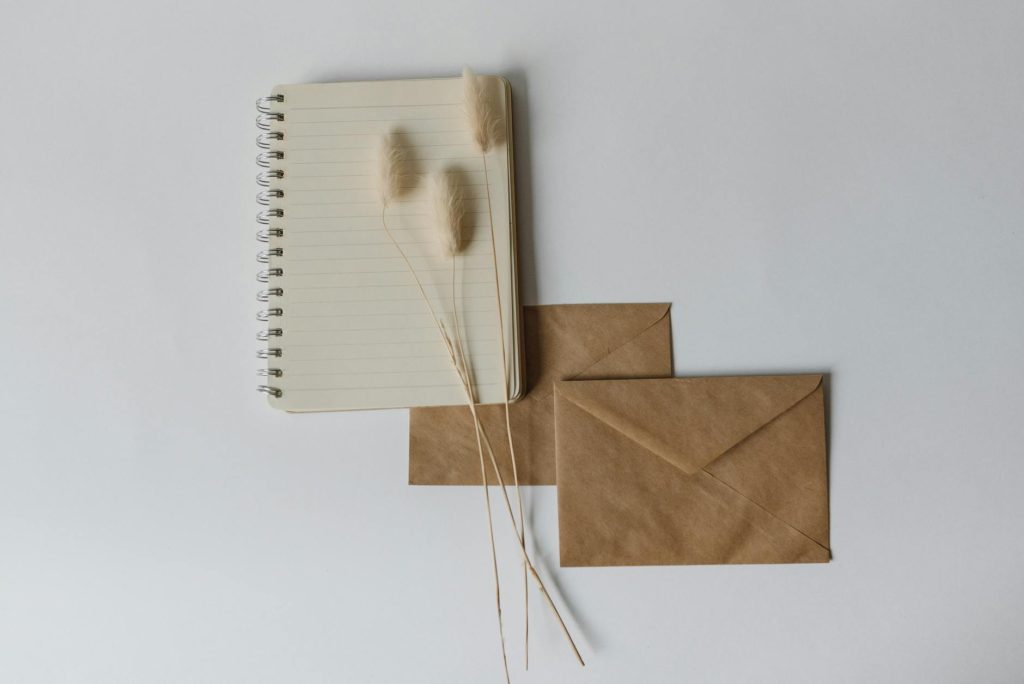Simple flat lay of a notebook with brown envelopes on a neutral background. Ideal for creative projects.