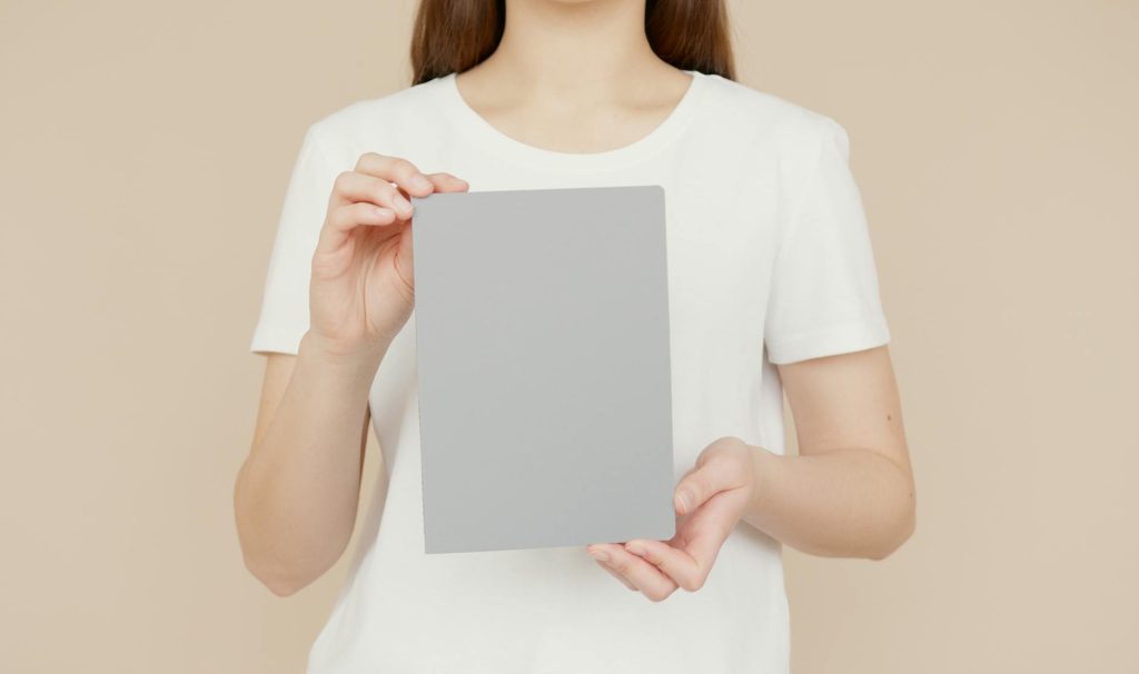 Close-up of a woman in a white shirt holding a blank notepad with copy space.