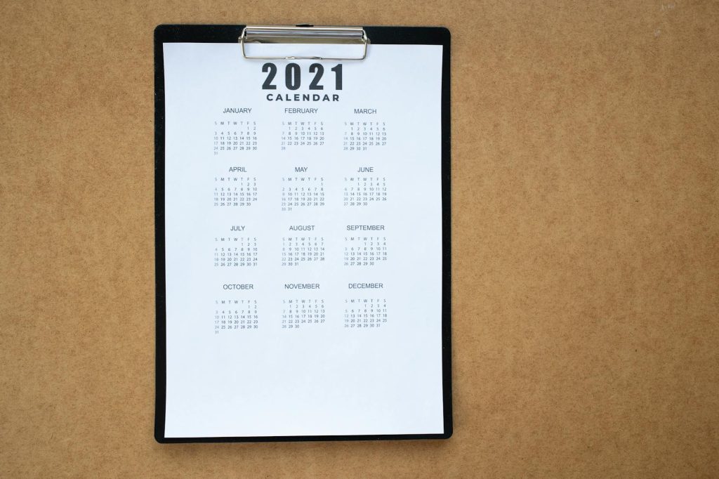 A 2021 calendar clipped to a black clipboard on a brown surface. Ideal for planning or scheduling visuals.