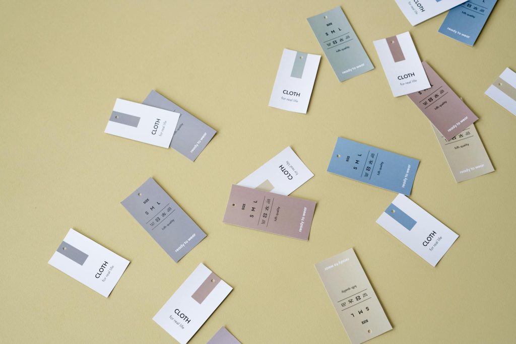 Scattered clothing tags in various colors on a yellow background, perfect for fashion design concepts.