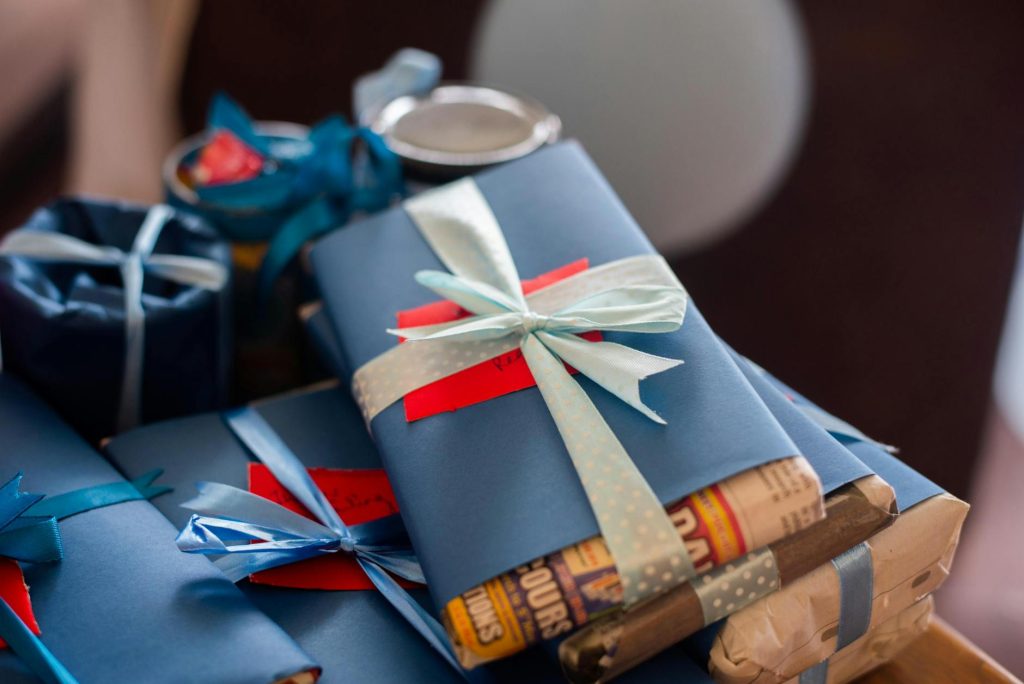 A stack of beautifully wrapped gifts with blue ribbons and red tags, perfect for celebrations.