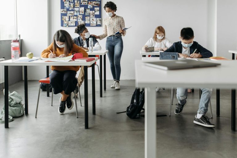A classroom scene with students and teacher wearing face masks, studying during a pandemic.