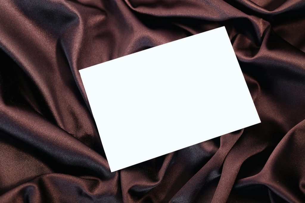 A blank card placed elegantly on rich, burgundy silk fabric with ample copy space.
