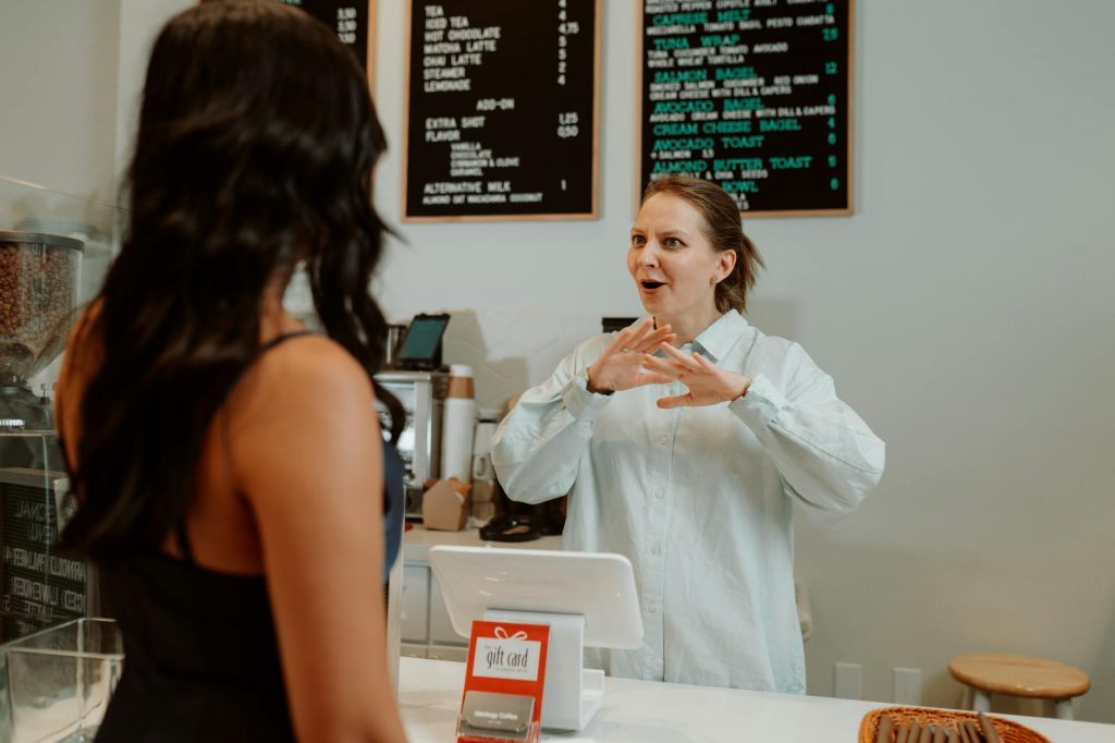 Barista interacting with customer at a coffee shop counter, vibrant atmosphere.