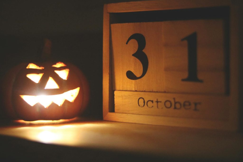 A glowing jack-o-lantern next to a calendar showing October 31, symbolizing Halloween celebration.