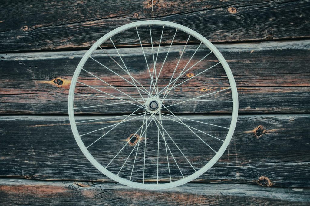 A rustic bicycle wheel displayed against an old wooden wall in Podlasie, Poland.