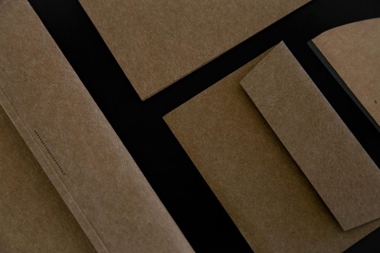 Flat lay of kraft paper envelopes and stationery on black background, showcasing eco-friendly materials.