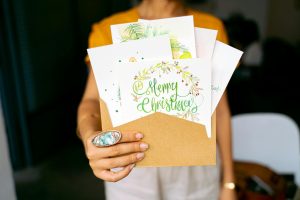 A close-up view of hands holding decorative Christmas cards in an envelope.
